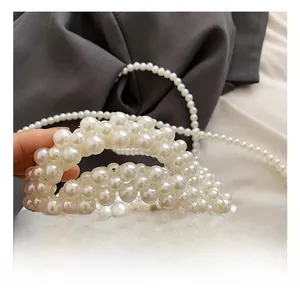 Detail of hand-woven cream white pearl handbag featuring a pink satin lining and bow