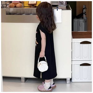 Détail d'un sac à main rond blanc associé à une robe t-shirt noire pour petites filles