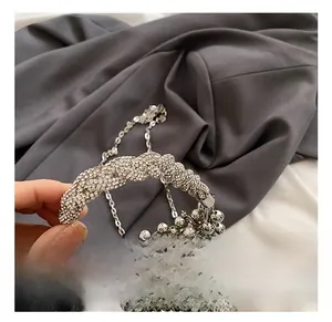 Detail of silver metallic beaded bucket bag featuring a rhinestone-encrusted handle strap