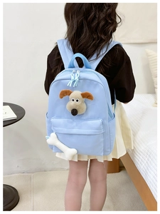 Detail of light blue kid's backpack featuring 3D plush puppy and bone zipper charm