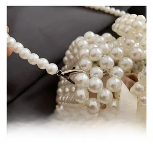Detailed close-up of high-quality silver metal lobster clasp on pearl woven shoulder bag