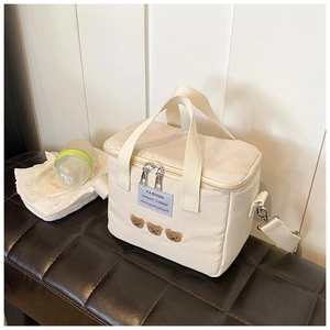 Detail of beige canvas diaper bag featuring cute bear embroidery and dual zippers