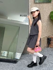 Détail d'un ensemble de sport gris foncé pour fille avec polo sans manches et jupe plissée