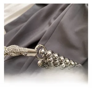 Macro detail of silver beaded bucket bag featuring a high-gloss metal spring hook connector