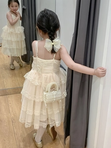 Detail of sweet cream lace tiered dress with matching pearl woven handbag for girls