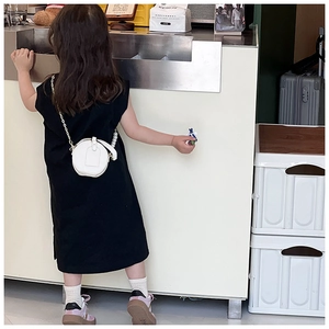 Mini sac rond blanc avec chaîne en perles porté comme accessoire sur une robe noire