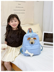 Detail of light blue kids backpack featuring 3D plush puppy face and bone keychain charm