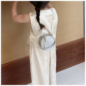 Mini sac à bandoulière rond pour enfants avec chaîne en perles porté par une petite fille