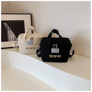 Detail of embroidered bears and fashion label on canvas diaper bag with adjustable strap