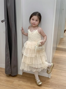 Detail of a white lace tiered dress for girls with a handmade pearl woven small handbag