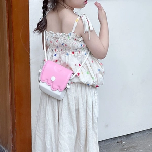 Mini sac à bandoulière rose et blanc pour enfants avec bord ondulé porté par un enfant