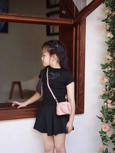 Détail d'un mini sac coquillage rose pour fille porté par un modèle dans un cadre extérieur