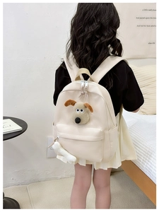 Detail view of cream leather kids backpack with cute plush 3D puppy and bone charm