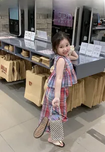 Detailed shot of a mini silver beaded bucket bag held by a girl in plaid outfit