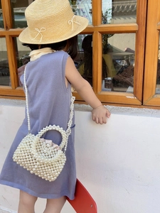 Toddler girl wearing a white woven pearl crossbody bag with pink satin drawstring lining