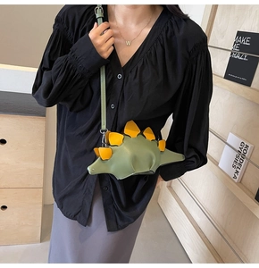 Detail of cute green stegosaurus dinosaur crossbody bag with yellow fins on a model
