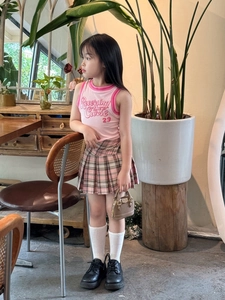 Détail d'un ensemble d'été rose pour enfant avec haut imprimé et jupe plissée à carreaux