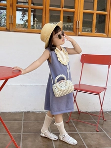 Girl in purple knitted dress with woven pearl handbag and straw hat in a retro scene