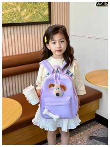 Detail view of purple kids backpack with 3D plush dog decoration and bone pendant charm