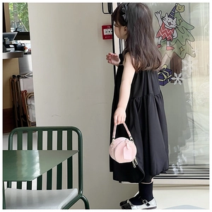 Mini sac à bandoulière rose rond porté avec une robe noire et des chaussures Mary Jane