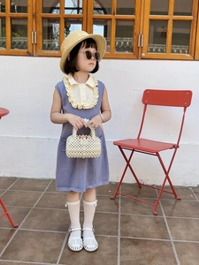 Close-up of girls purple knit dress with beige ruffled collar and pearl beaded handbag