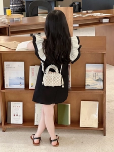 Detailed view of white pearl woven handbag with elegant handle and long shoulder strap