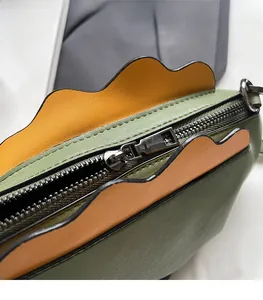 Détail du zip métallique et des bords ondulés sur sac bicolore vert et orange
