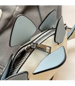 Close-up of smooth metal zipper and contrasting leather stitching on dinosaur crossbody bag