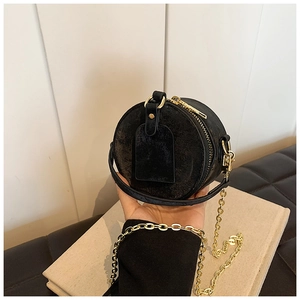 Détail d'un petit sac rond noir en cuir avec texture vintage et chaîne dorée
