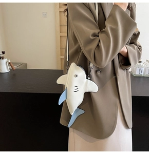 Gros plan d'un sac bandoulière blanc en forme de requin avec nageoires bleues et clips