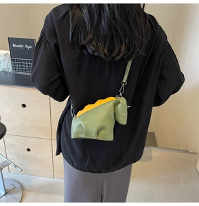 Détail d'un sac à bandoulière en forme de dinosaure vert mignon avec des écailles jaunes