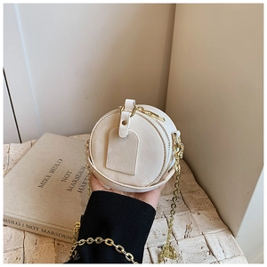Détail du petit sac rond blanc pour enfant avec bandoulière chaîne dorée et fini mat