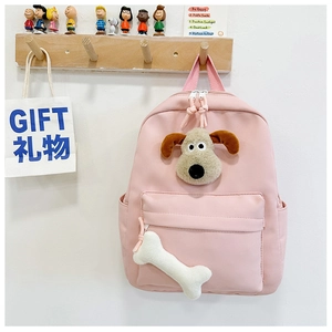 Detail of pink school backpack featuring plush puppy face and bone keychain accessory