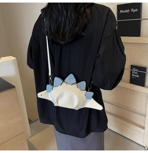 Detail of cute dinosaur shaped crossbody bag in cream PU leather with blue accents