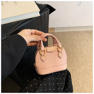 Vue macro d'un mini sac coquille rose en cuir grainé avec détails de logo en métal doré