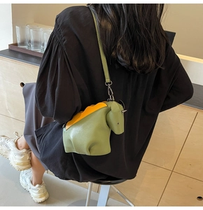 Gros plan du sac dinosaure vert olive avec épines orange et texture détaillée du cuir