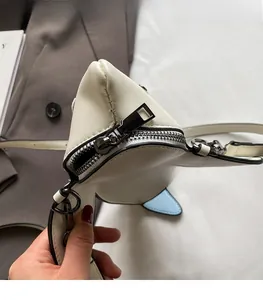 Détail du mini sac en cuir blanc avec fermeture éclair en métal gris et finition des bords