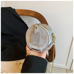 Gros plan d'un sac bandoulière rond gris clair avec texture marbre et chaîne dorée