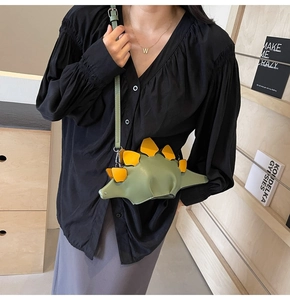 Chic green dinosaur crossbody bag with yellow scales shown on a model outfit style