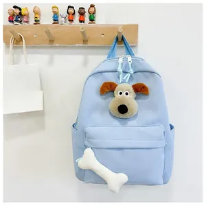 Close-up of light blue kids backpack featuring 3D cartoon dog head and bone pendant