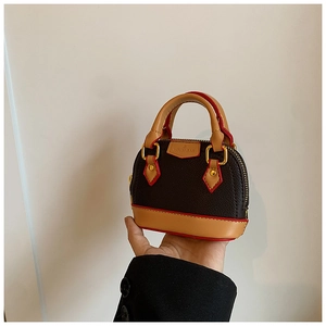 Vue détaillée du mini sac coquillage en cuir marron foncé tenu à la main