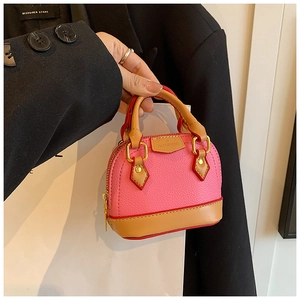 Gros plan détaillé d'un sac bandoulière rose en forme de coquille au cuir grainé