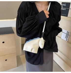 Vue de côté du sac bandoulière en forme de cheval crème et bleu porté par un mannequin