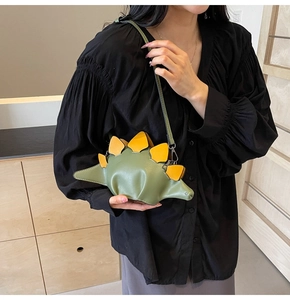 Detail view of the creative green dinosaur shoulder bag with yellow fins on a model