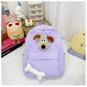 Detail of light purple canvas backpack featuring a plush dog head and bone charm