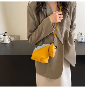 Détail du sac bandoulière dinosaure jaune avec pointes bleues sur tenue de mannequin