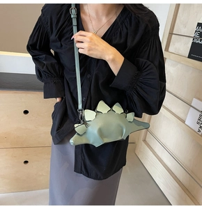 Detail of light green stegosaurus dinosaur shoulder bag with silver metal buckles