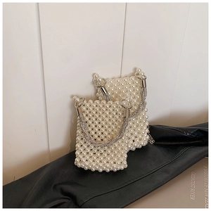 Detail of beaded mini bucket bag with pearl texture and silver metal ring handle