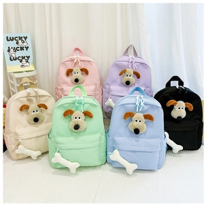 Flat lay of colorful kindergarten backpacks featuring 3D cartoon dog plush and bone charm