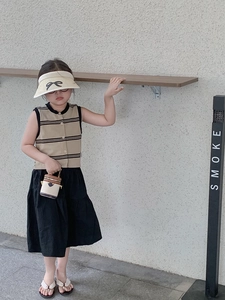 Schickes Mädchen-Outfit mit schwarzem Faltenrock, Strickweste und Mini-Handtasche